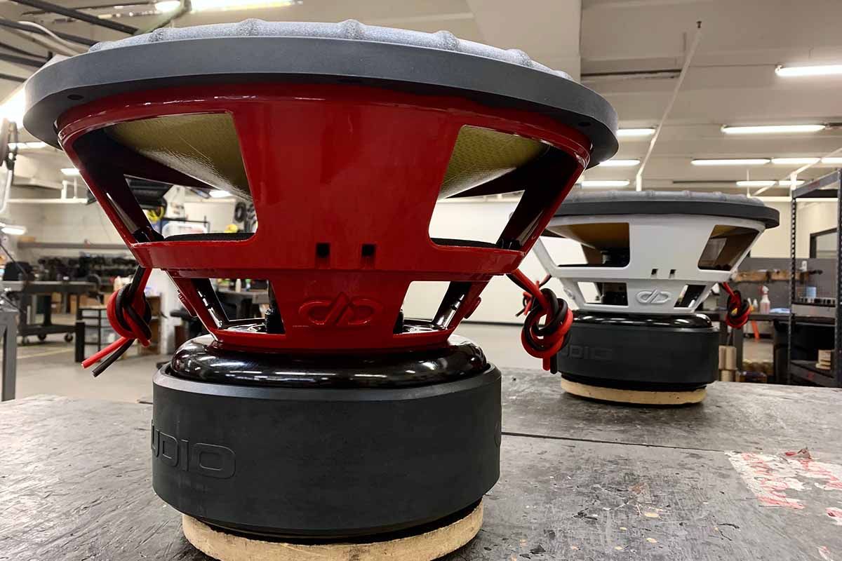 Two USA Made subwoofers - one with a red powder coat basket and red DDA embossed logo, the other with a white powder coat basket and white DDA embossed logo